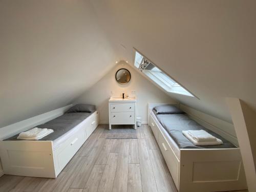 エグモント・アーン・ゼーにあるCozy Tiny House Egmond aan Zee- 500m from Beach-North Seaのベッド2台、デスクが備わる屋根裏部屋です。