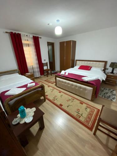 ein großes Schlafzimmer mit 2 Betten und einem Tisch in der Unterkunft Guesthouse Mehmeti in Valbonë