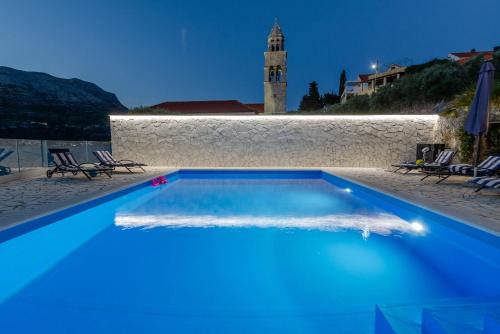 a blue swimming pool with a clock tower in the background at Villa Gabriela in Korčula