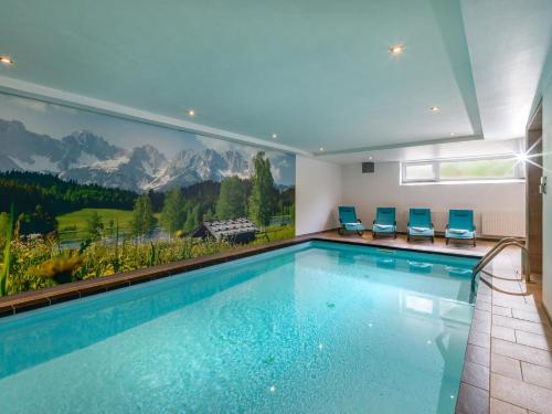 a swimming pool in a house with a mural of mountains at Haus Tirol in Brixen im Thale