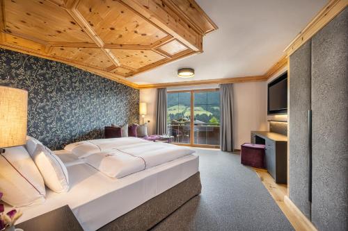 a bedroom with a large bed and a television at Der Böglerhof - pure nature spa resort in Alpbach