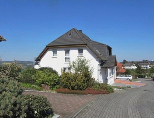 a white house with a black roof on a street at Schöne große Ferienwohnung im Mittelrheintal nahe Loreley in Bornich