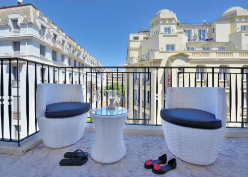 three chairs and a table and some shoes on a balcony at Appartement Rue Grimaldi in Nice