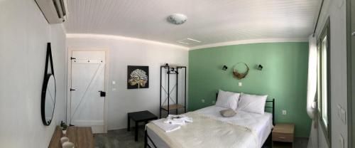 a bedroom with a white bed and a green wall at Akrogiali House in Skala Kallirakhis