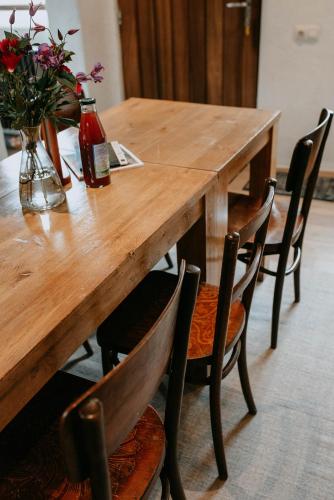 a wooden table with chairs and a vase of flowers at Beautiful holiday home in renovated farm 30 mins from Pairi Daiza in Geraardsbergen
