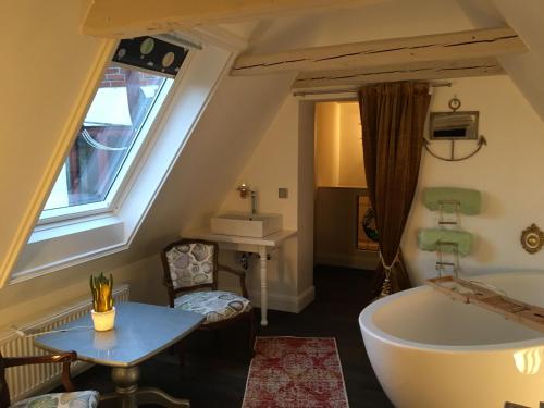 a bathroom with a tub and a table and a chair at Townhouse in Friedrichstadt