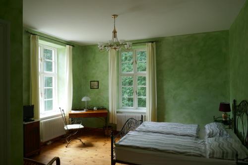 a bedroom with a bed and a desk and windows at Landhaus Schloss Kölzow in Kölzow