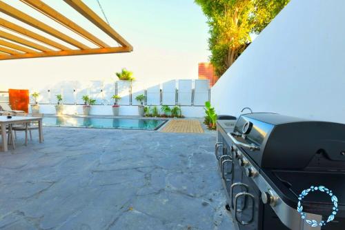 a barbecue grill on a patio next to a pool at Shani House Of Style SEATARA VILLA in Eilat