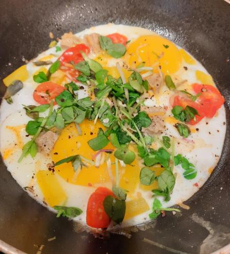 a fried egg with tomatoes and green onions in a pan at Willow House Inn B&B in Pictou
