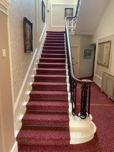 a stairway with red carpeting and a red carpeted staircase at Broughton Craggs Hotel in Cockermouth