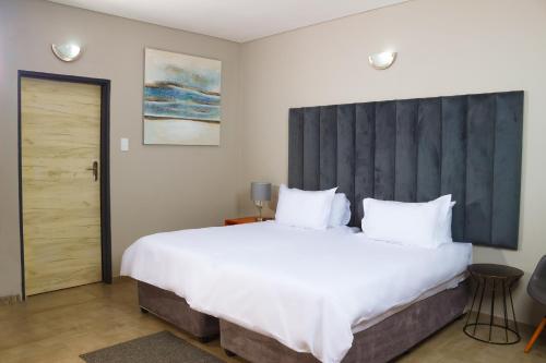 a bedroom with a large white bed with a large headboard at Ndalo Lodge Oshoek 