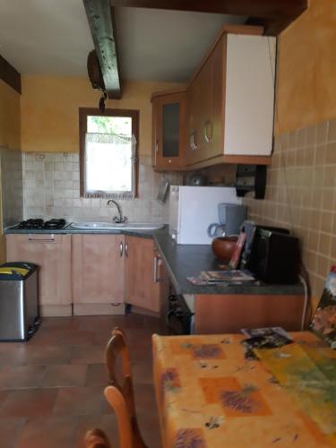 a kitchen with wooden cabinets and a table in it at le vieux mas du domaine de Pontet-Fronzele in Lagorce