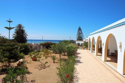 a garden with plants and a building and the ocean at Casa Mia in Ouled Kacem