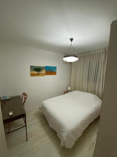 a bedroom with a white bed and a table at צימר דירת בכור in Yavneʼel