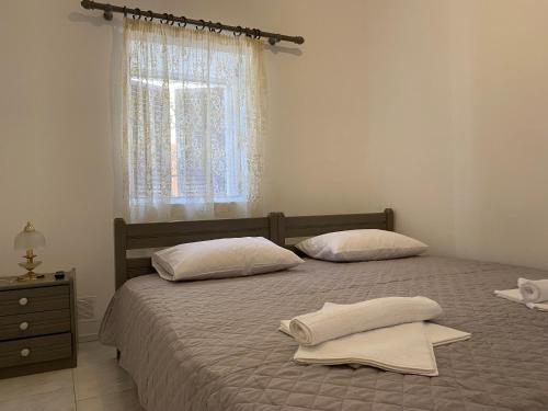 1 dormitorio con 2 camas con almohadas blancas y ventana en Casa Plakes, en Ermoupoli