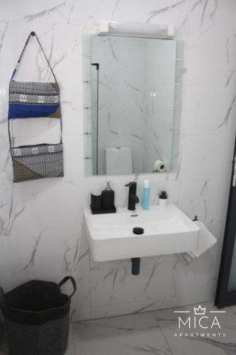 a white bathroom with a sink and a mirror at Mica Apartments in Sere Kunda