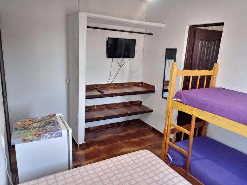 a room with a bunk bed and a tv at Pousada Chalés Vereda do Sol in Ubatuba
