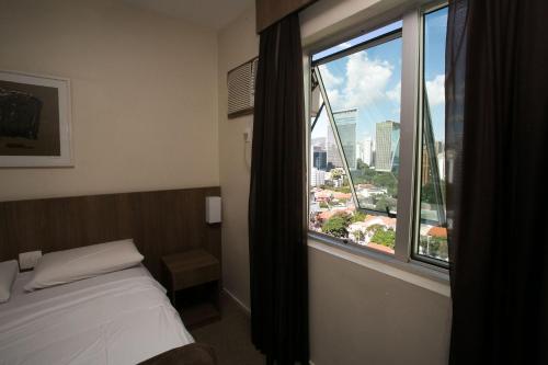 um quarto com uma cama e uma grande janela em Locking´s Barro Preto 1 em Belo Horizonte