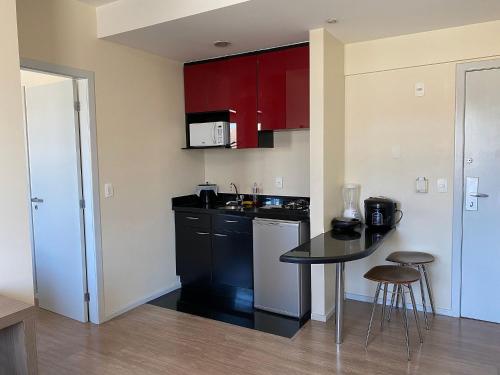 a small kitchen with a black counter top and red cabinets at LK Barro Preto 1 in Belo Horizonte