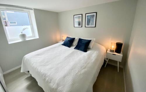 Un dormitorio con una cama blanca con almohadas azules y una ventana en Two bedroom apartment near the city centre. en Tromsø