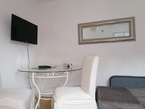 a room with a table with a tv and a chair at Charmante Maisonnette indépendante avec parking 5 mn Rouen in Franqueville-Saint-Pierre