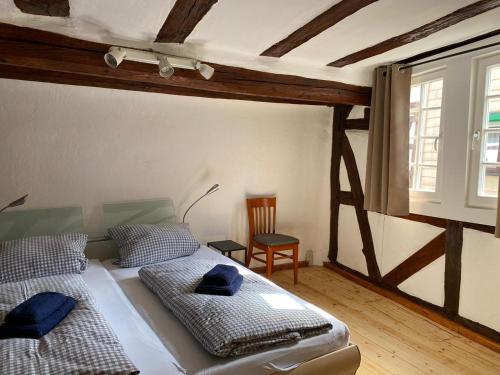 1 dormitorio con 2 camas, silla y ventana en Ferienwohnung Obergasse en Zwingenberg