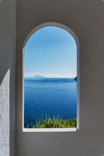 an arched window with a view of the ocean at Hotel Punta Scario in Malfa