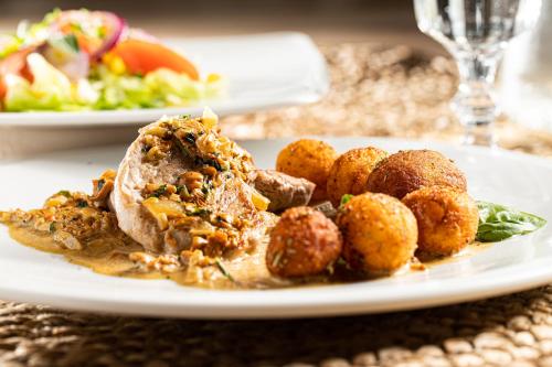 a plate of food with meat and potatoes on a table at Hotel Ukiel Wellness & SPA in Olsztyn