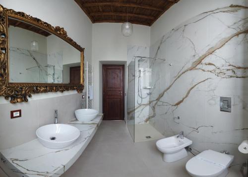 een badkamer met een wastafel, een toilet en een spiegel bij Palazzo Forlani in Capranica