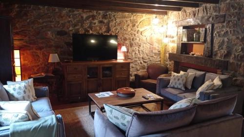 a living room with couches and a tv at Posada Reserva Verde in Bárcena Mayor