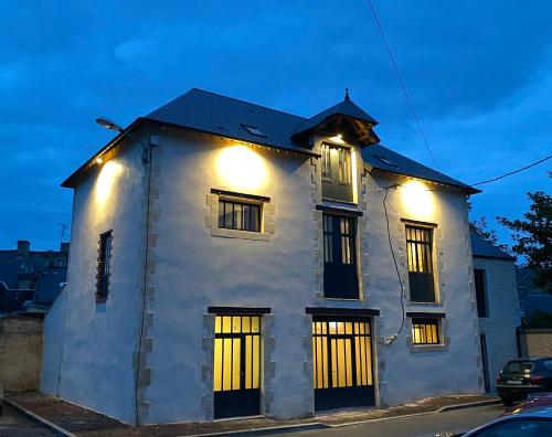 une maison blanche avec des lumières au-dessus dans l'établissement L'ATELIER DU VIEUX BOIS Spa, à Bayeux