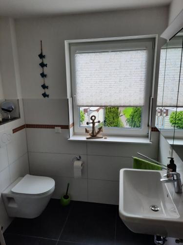 a bathroom with a toilet and a sink and a window at Zum Landmann in Luhdorf