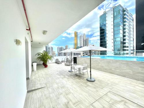 巴拿馬城的住宿－Hotel Mio Panamá，大楼内带游泳池和遮阳伞的阳台