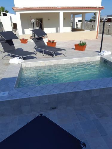 a swimming pool with two lounge chairs next to it at Fronte Mare in Avola
