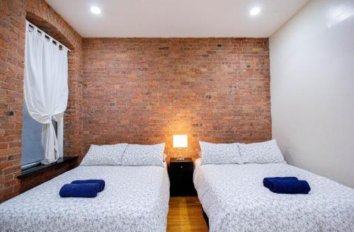 ニューヨークにあるスタジオ プラス 1ベッドルーム APTのレンガの壁の客室内のベッド2台