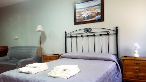 a bedroom with a bed and a chair with towels on it at Apartamento Loft III Select Real Caldas de Reis in Caldas de Reis