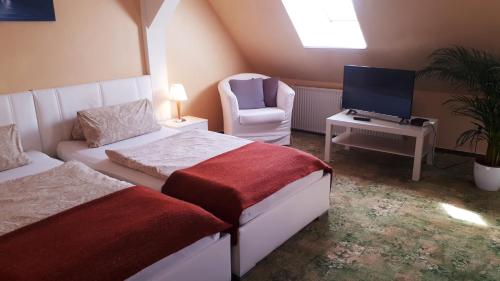 a bedroom with two beds and a tv and a chair at Hotel Krone Lindow in Lindow