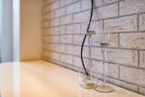 two wine glasses sitting on a table next to a brick wall at Lux Apartment in white in Gdańsk