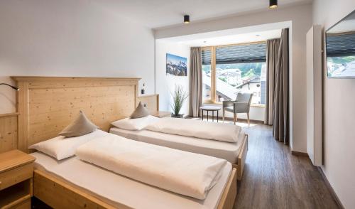 2 camas en una habitación con mesa y sillas en Residence Tombla, en Ortisei