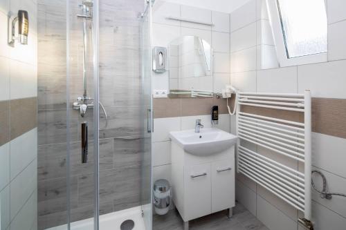 a white bathroom with a sink and a shower at Penzion Zuzana in Ružomberok