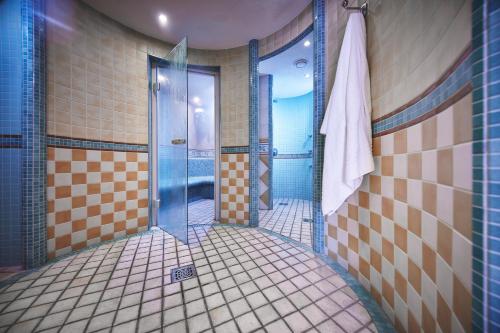 a tiled bathroom with a shower with a glass door at Rüters Parkhotel in Willingen