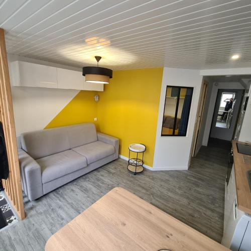 - un salon avec un canapé et un mur jaune dans l'établissement T2 GUYNEMER RDC WIFI Plage à 80m Linge de lit fourni, à Les Sables-dʼOlonne