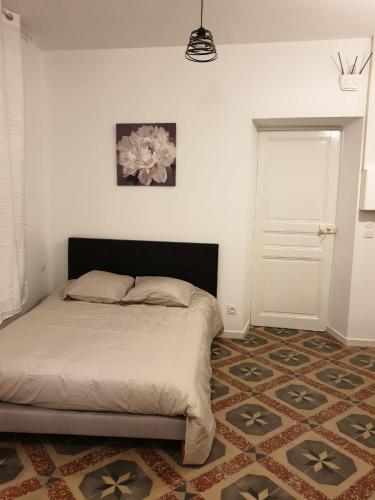 une chambre avec un lit et un mur blanc dans l'établissement Studio Boffil centre historique Perpignan, à Perpignan