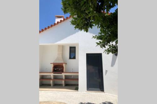 a white house with a door and a fireplace at Grandfather's House in Tábua
