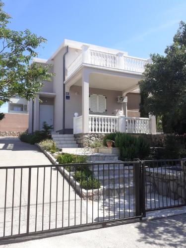 a white house with a fence in front of it at Apartment Cesarica in Cesarica