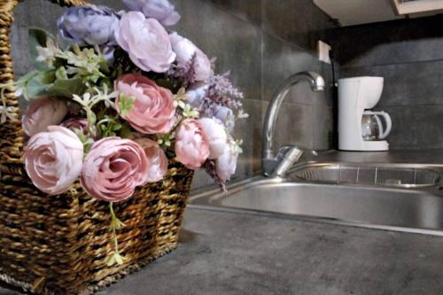 a basket filled with pink and purple flowers next to a sink at Thea family apartments 3 in Yenion