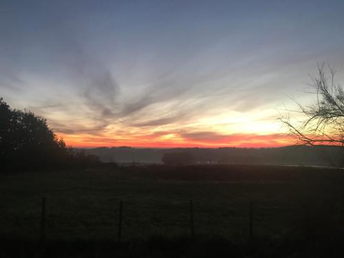 a sunset in a field with a fence at Maison de vacances Gers in Manciet