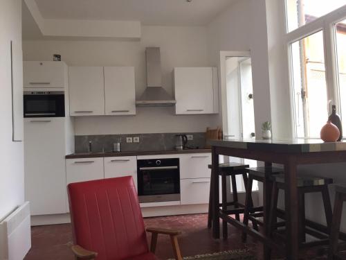 une cuisine avec des placards blancs et une table avec des chaises rouges dans l'établissement Typique T2 Terrasse situé Quartier Panier Vieux Port, à Marseille
