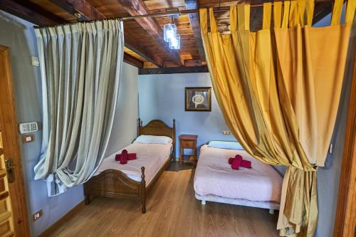 two beds in a room with yellow curtains at Garai Etxea, casa adosada en la montaña in Arrankudiaga