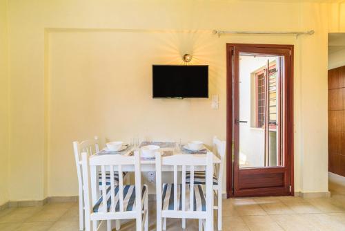 a white table with chairs and a television on a wall at Harmony House in Platanias